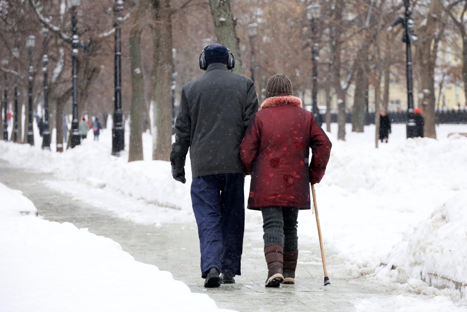 Elderly person walking in winter with support