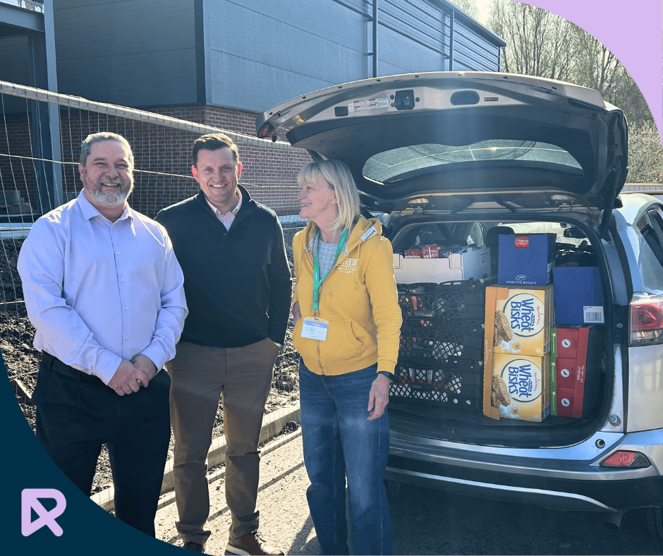 Routes Healthcare team presenting a boot-full of food and toiletry donations to Rochdale Foodbank.